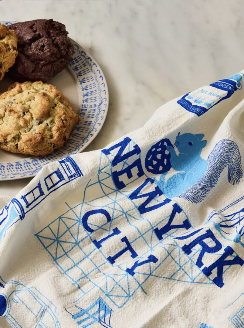 A tea towel with New York City designs and a cookie on a plate.