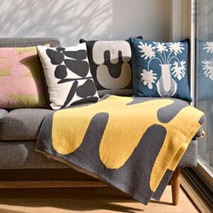 Cozy sofa adorned with colorful patterned pillows and a yellow throw blanket.