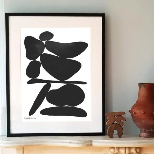 Abstract black shapes framed in white, displayed on a shelf.