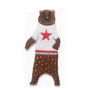 A knitted brown bear wearing a white tank top with a red star.