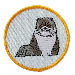 A circular embroidered patch featuring a sitting gray and white cat.