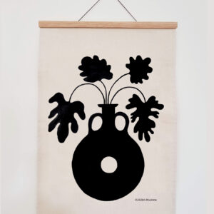 Minimalist wall art with black silhouette of a vase and leaves on beige fabric.